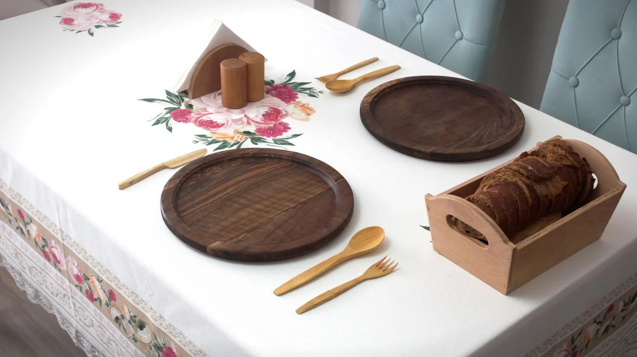 about-02 Chic table setup featuring wooden platters, utensils, and floral tablecloth decor.