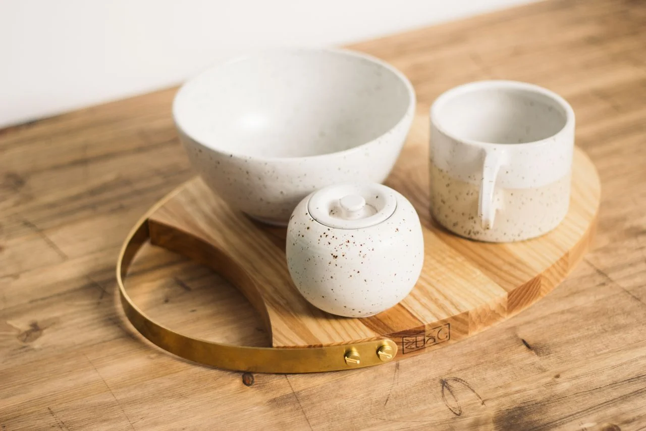 From above stylish minimalistic tea set of light ceramic in dark spots served on oval wooden board
