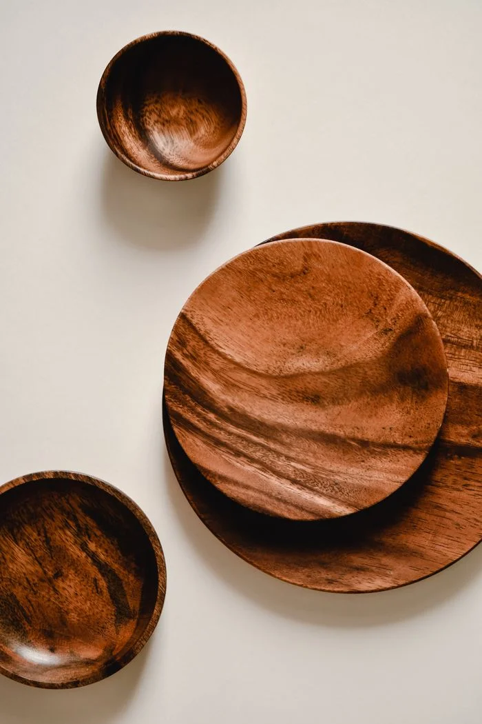 Top view of minimalist wooden bowls and plates on a white background, showcasing elegant kitchenware design.